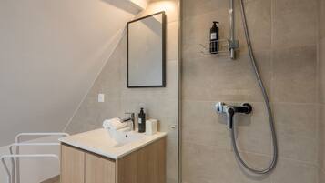 Une salle de bain moderne avec une douche, un lavabo et un miroir.