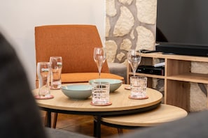 A dining area with a round table, multiple glasses, bowls, and a television in the background. - A Charming Stay in the Towers—100 m from the Castle—Sleeps 6 (Blandy)