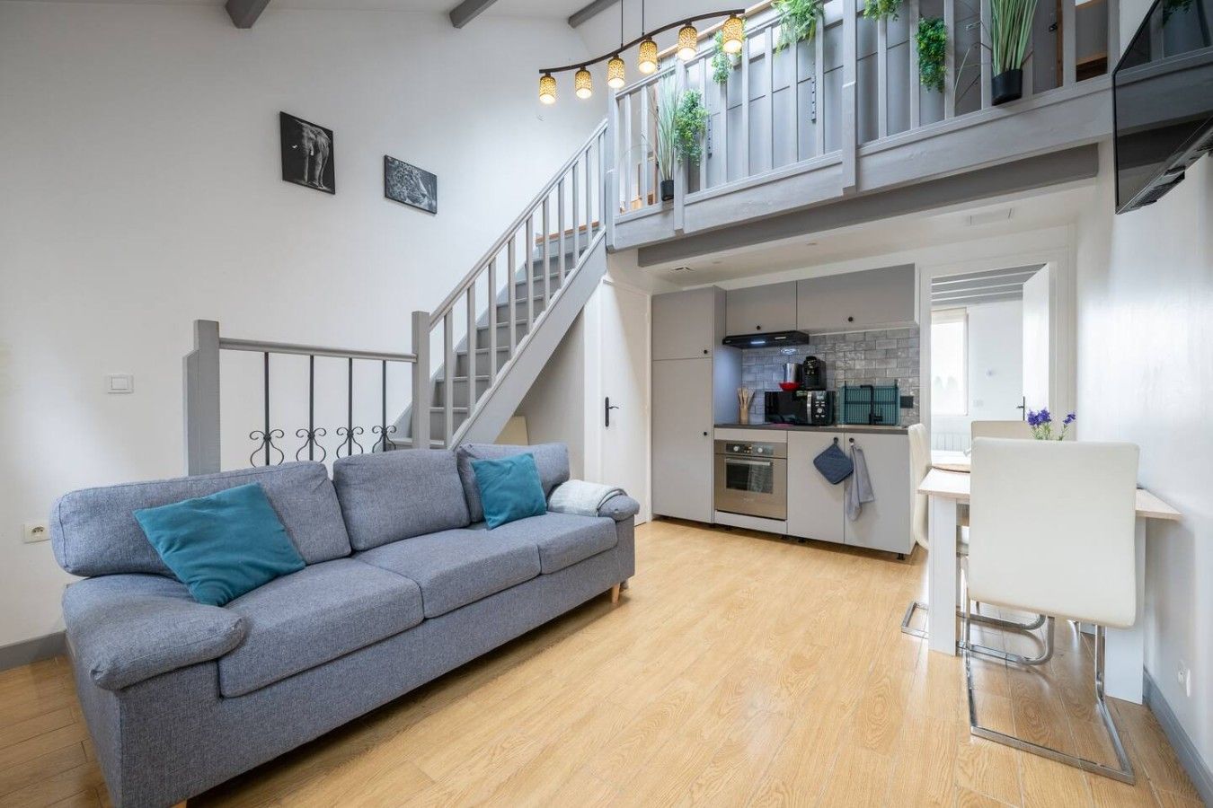 Ein modernes Wohnzimmer mit einem grauen Sofa, einer Treppe, einer Küche und einem Essbereich.