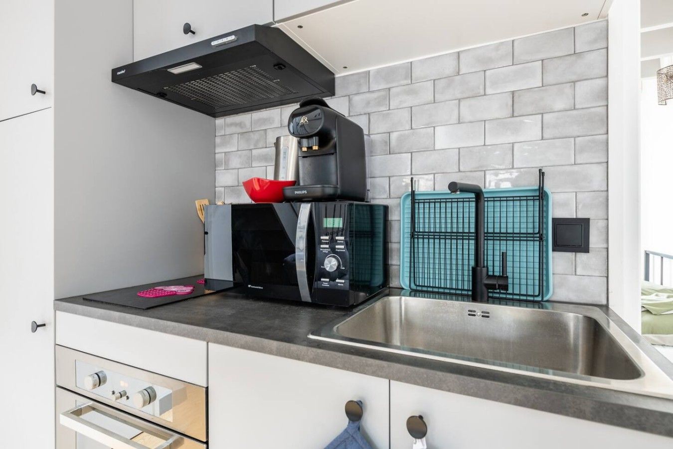 Eine moderne Küche mit integriertem Mikrowellenherd, einer Kaffeemaschine und einem Spülbecken mit Armatur.
