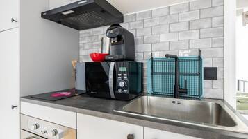 Eine moderne Küche mit integriertem Mikrowellenherd, einer Kaffeemaschine und einem Spülbecken mit Armatur.