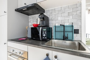 A modern kitchen with a built-in microwave, a coffee maker, and a sink with a faucet. - Le Clos des Chevaux - Stylish Duplex with Garden (La Celle-sur-Morin)