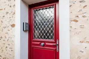 Una puerta roja con un cerrojo de seguridad metálico y un teclado de números en la pared contigua.