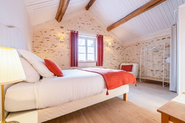 Un dormitorio con cama, mesita de noche, lámpara, ventana con cortinas y armario.
