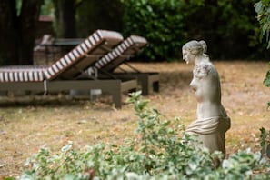 A statue of a classical figure in a garden with a pool and lounge chairs in the background. - House, Lot | Hot Tub • Fire pit • Art & Deco (Bourdenay)
