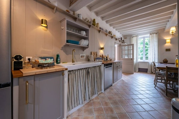 Una cocina con una isla central, estantes empotrados y un comedor con mesa y sillas.