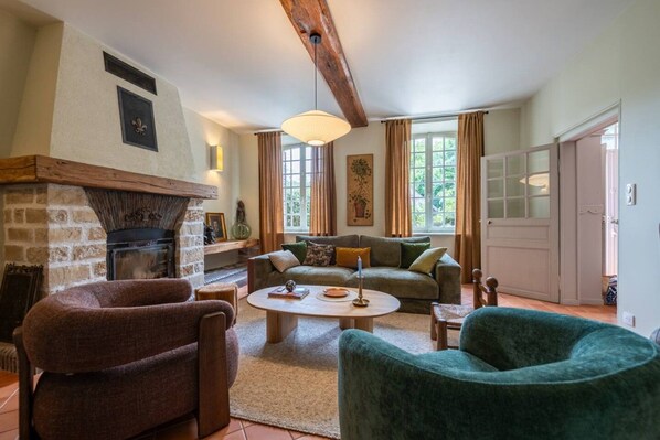 A cozy living room with a fireplace, a sofa, a coffee table, and a green armchair.