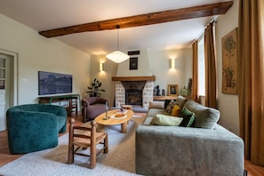Una sala de estar acogedora con chimenea, un sofá, una mesa de centro y un televisor.