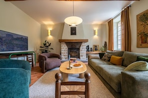 Ein gemütliches Wohnzimmer mit Kamin, einer Couch, einem Sessel und einem Fernseher.