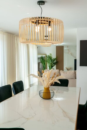 A modern dining area with a marble table, black chairs, a woven pendant light, and a vase with dried flowers. - Le Panoramique | Exceptional Home • 12 trips (Crécy-la-Chapelle)