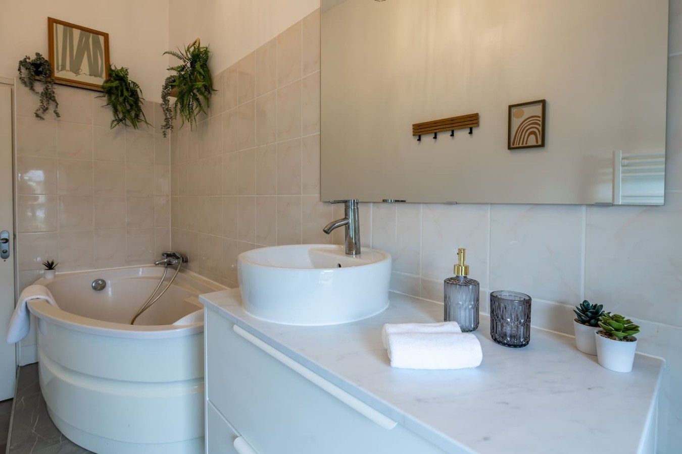 A modern bathroom with a freestanding bathtub, two sinks, and a vanity with a mirror.