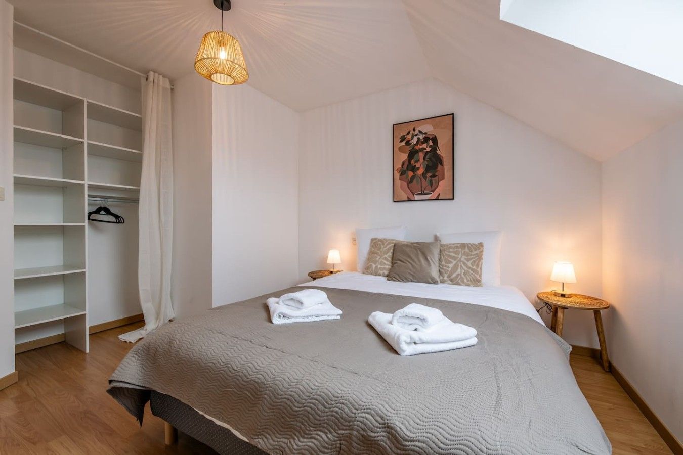 Une chambre avec un grand lit, une armoire, des lampes de chevet et un tableau au mur.