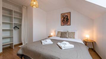 Une chambre avec un grand lit, une armoire, des lampes de chevet et un tableau au mur.