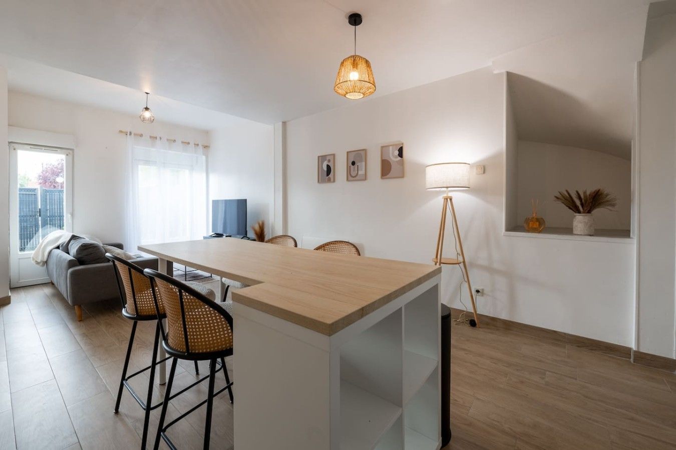 Una cucina moderna con isola centrale, sgabelli da bar, tavolo da pranzo e lampada a sospensione.