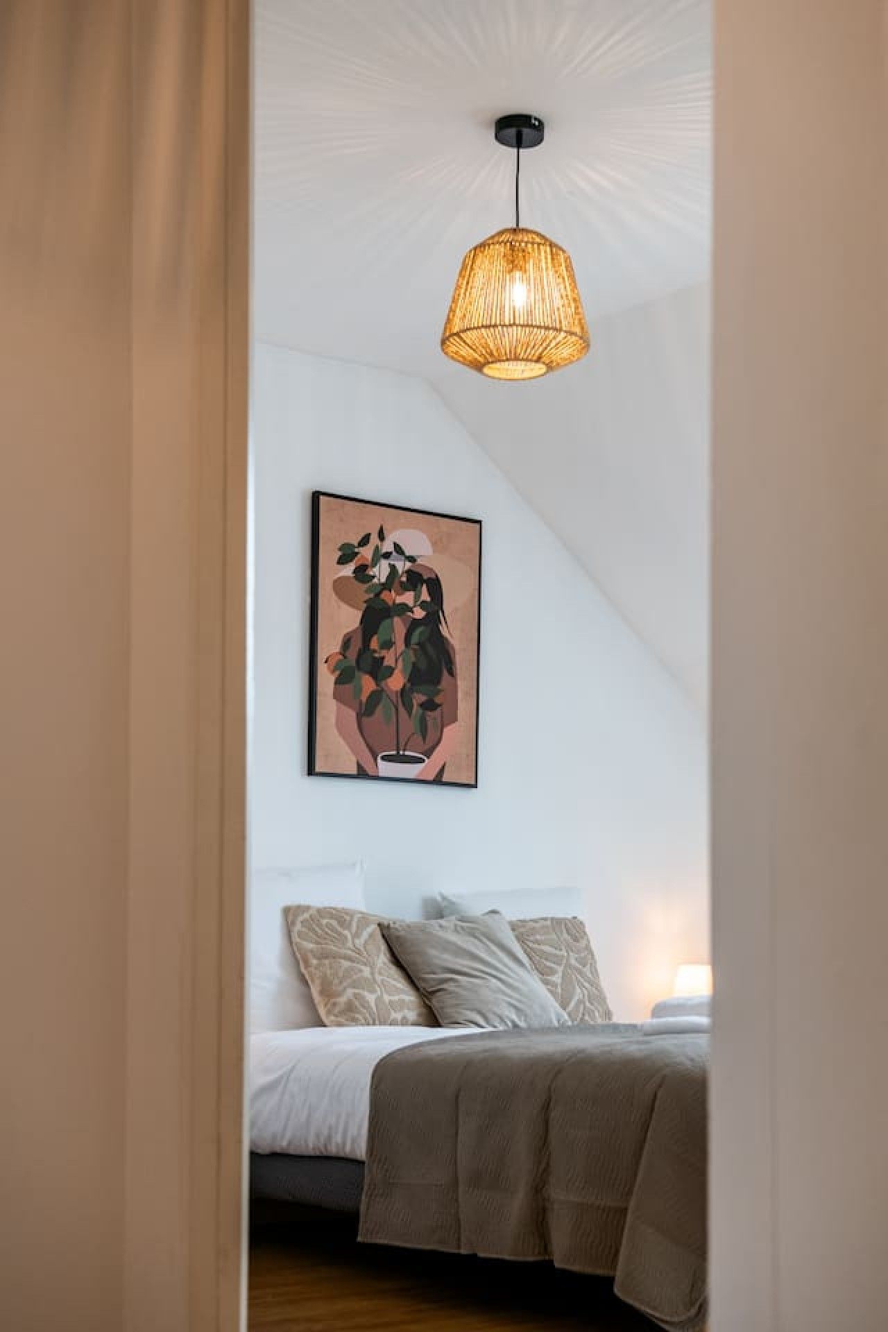 Ein Schlafzimmer mit einem Bett, einer Hängelampe und einem gerahmten Kunstwerk an der Wand.