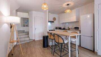 A modern kitchen with a central island, white cabinetry, and a dining area with four chairs.