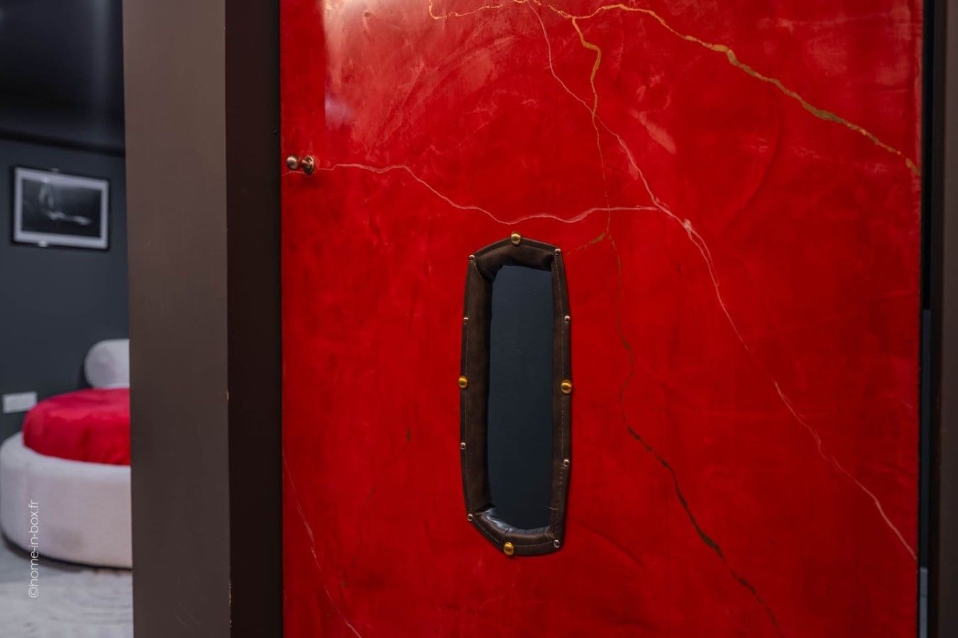 A red door with a rectangular mirror and a small window.