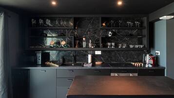 Een moderne keuken met donkere kastjes, een marmeren achterwand en een centraal eiland met krukken.