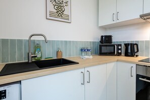 A kitchen with a sink, a microwave, a coffee maker, and a dishwasher. - A Little Getaway—Air-conditioned home, barbecue, renovated (Longueville)