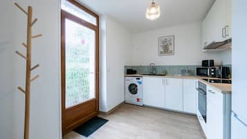 A compact kitchen with a washing machine, a microwave, and a sink.