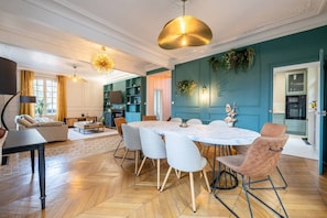 A modern living room with a dining area, a fireplace, and a kitchen visible through an open door. - Villa Les Roches - Comfort - Relaxation - Pool (La Ferté-Gaucher)