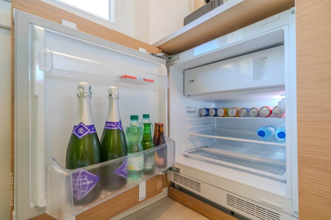 Ein offener Kühlschrank mit Flaschen und Dosen darin.