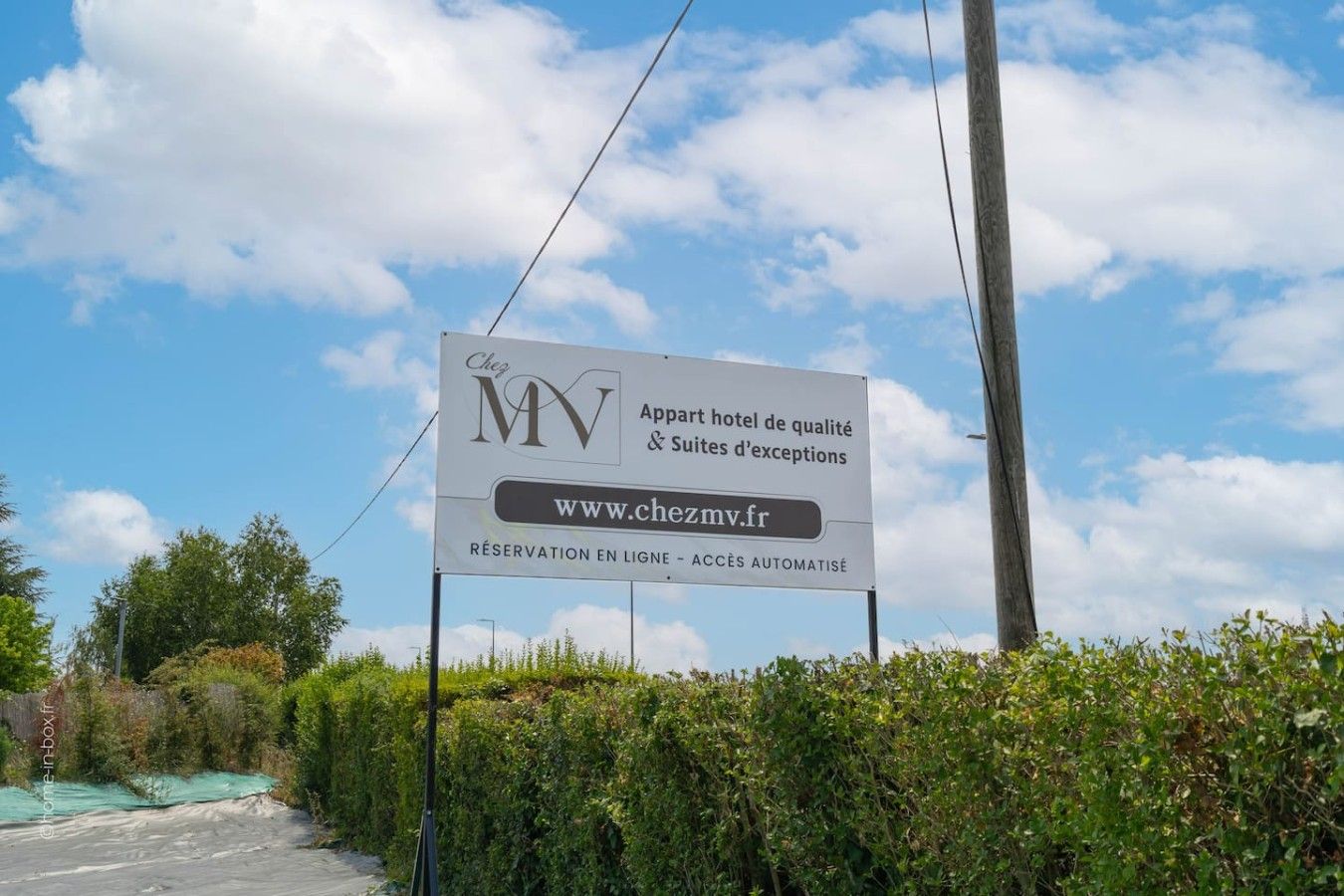 Schild für Chez MV, ein Hotel mit aufgeführter Webseite, erwähnt Online-Reservierung und automatisierten Zugang.