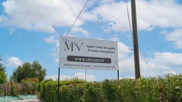 Schild für Chez MV, ein Hotel mit aufgeführter Webseite, erwähnt Online-Reservierung und automatisierten Zugang.