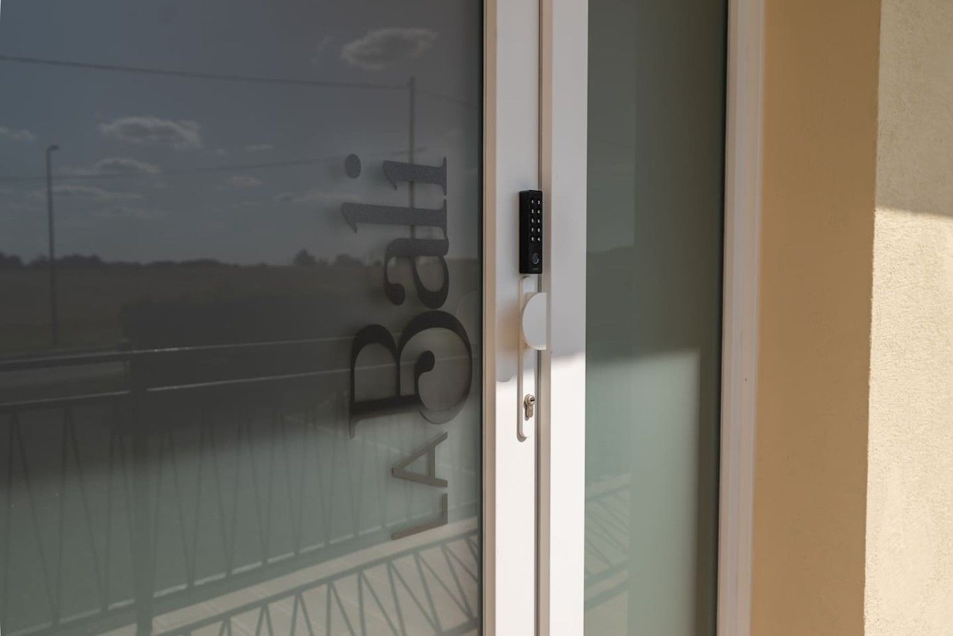 Une porte en verre à motifs dépolis et dotée d’un clavier pour l’ouverture à code.