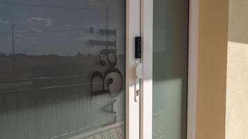 Une porte en verre à motifs dépolis et dotée d’un clavier pour l’ouverture à code.