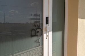 Une porte en verre à motifs dépolis et dotée d’un clavier pour l’ouverture à code.