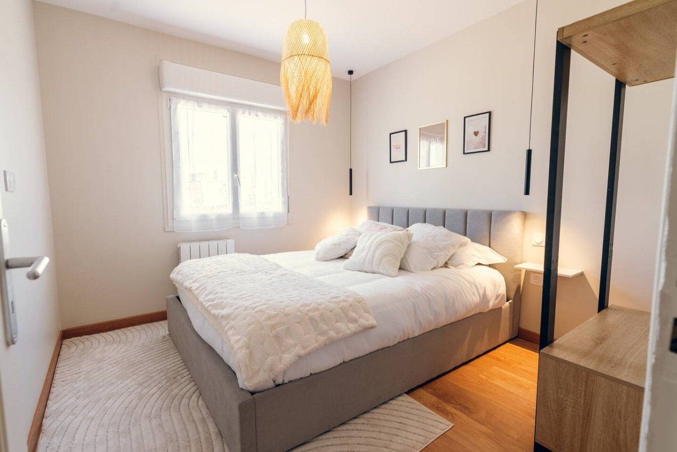 Een slaapkamer met een bed, nachtkastje, lamp en hanglamp.