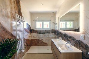 Une salle de bain moderne avec une douche, deux lavabos et un grand miroir.