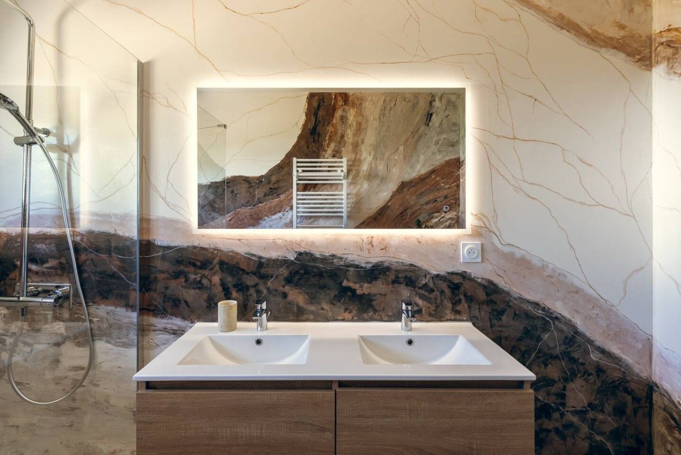 A bathroom with a double sink vanity, a large mirror, and a shower area.