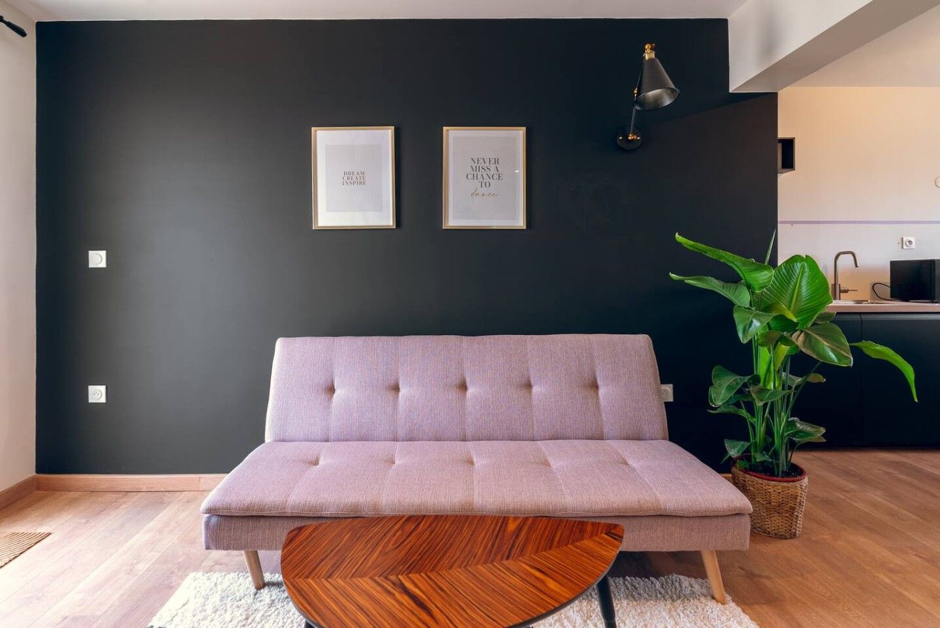 Un salon moderne avec un canapé, une table basse ronde en bois et une plante en pot.