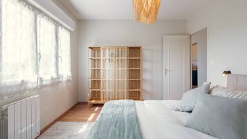 A bedroom with a bed, a wardrobe, and a window with sheer curtains.