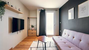 Een moderne woonkamer met een flatscreen televisie, een bank, een salontafel en een trap naar een bovenverdieping.