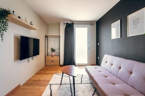 Una sala de estar moderna con un televisor de pantalla plana, un sofá, una mesa de centro y una escalera que sube a un piso superior.