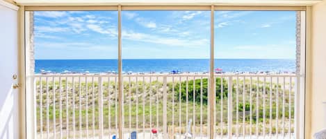 A balcony with a view of a beach and ocean.
