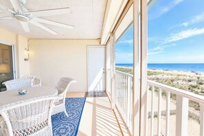 Ein Balkon mit Blick auf den Strand, ein Deckenventilator und ein Tisch mit Stühlen.