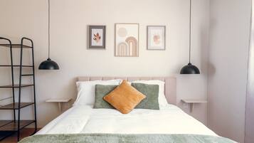 Une chambre à coucher avec un lit, des oreillers, une couverture, une échelle et des œuvres d’art murales.