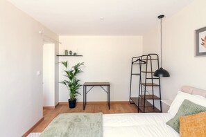 Une chambre à coucher comprenant un lit, une table de chevet, une étagère suspendue, une plante en pot et une lampe sur pied.
