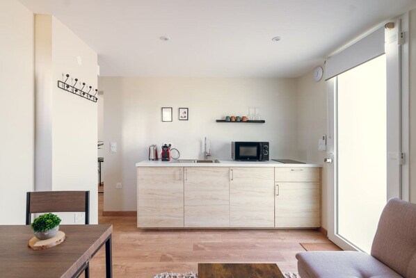 A modern kitchen with a microwave, sink, and cabinets. There is a dining table with a plant and a chair. - The essentials, air-conditioned and renovated (La Ferté-Gaucher)