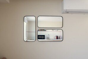 Trois miroirs de différentes tailles, fixés au mur.