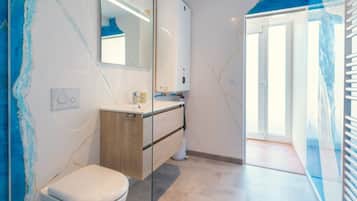 Ein modernes Badezimmer mit Toilette, Holzwaschtisch und einer Duschkabine aus Glas.