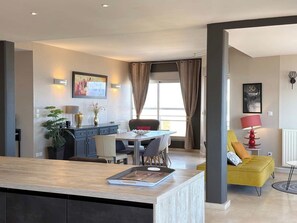Un espace de vie moderne comprenant un coin repas, une cuisine et un canapé jaune.