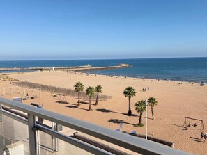 A beach with a clear view of the sea, a wooden jetty, and palm trees. - Beachfront 3 Bedroom Apartment with Panoramic Sea View and Balcony (Valras-Plage)