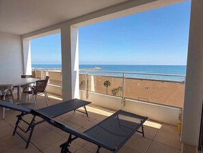 A balcony with a table and chairs, overlooking a beach and the sea. - Beachfront 3 Bedroom Apartment with Panoramic Sea View and Balcony (Valras-Plage)