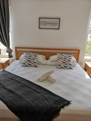 A neatly made bed with two pillows, a rolled towel, and a framed picture on the wall. - Case Damare Coralstone 2 (Las Terrenas)