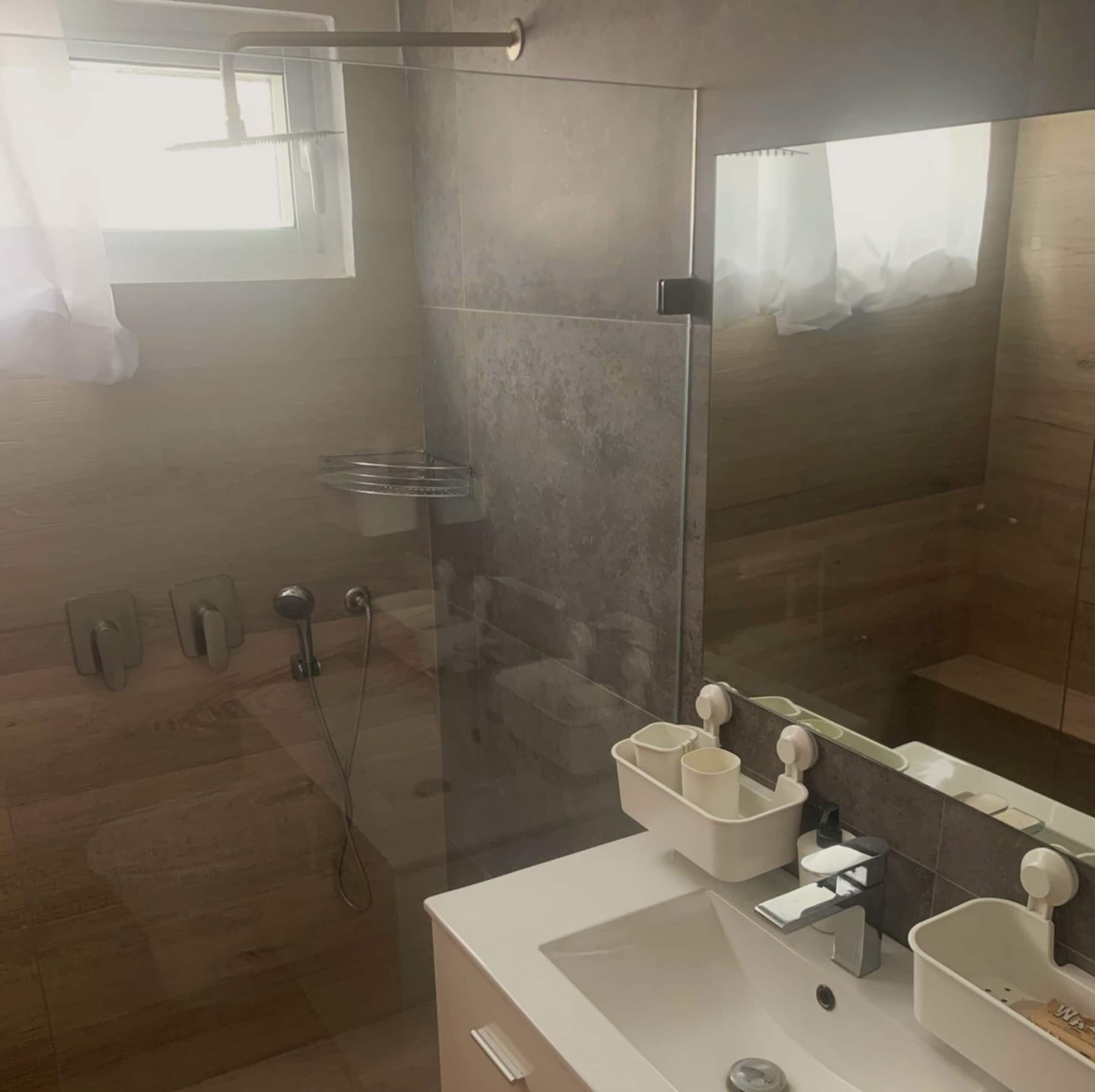 Une salle de bain moderne avec une douche à parois de verre, un lavabo blanc et un miroir.